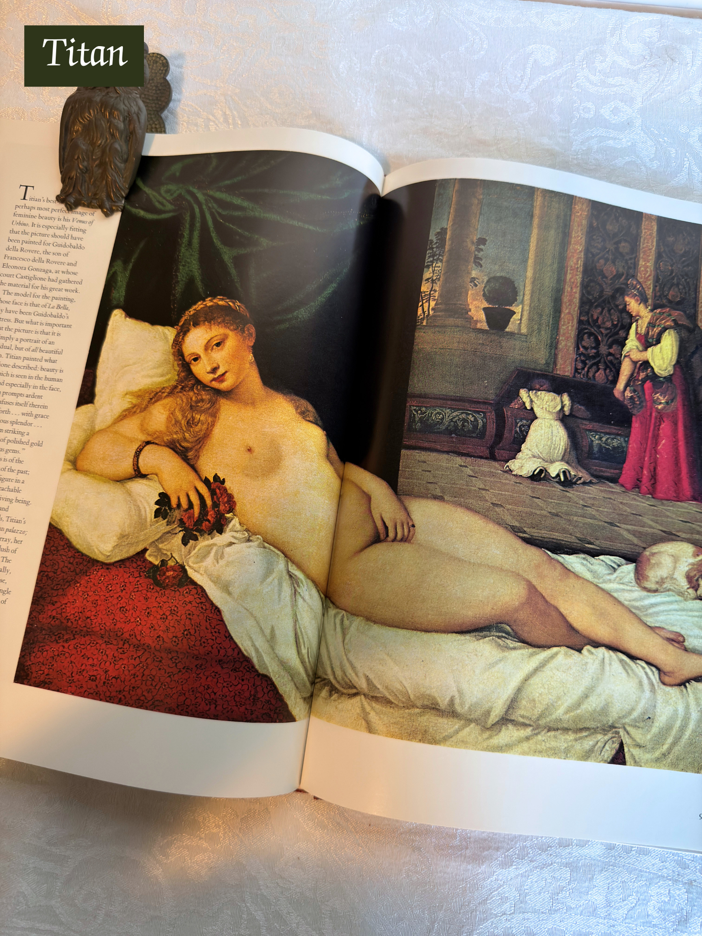 Open book showing a classical painting of a nude woman reclining.