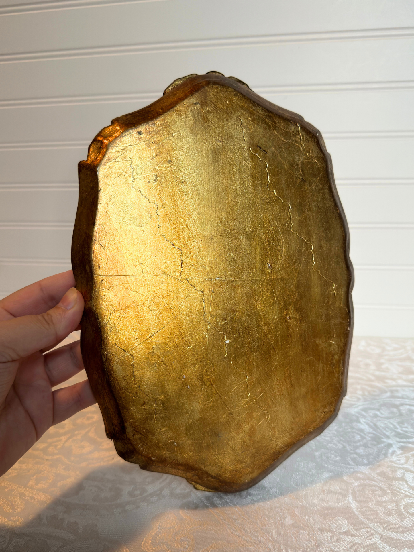 back of tray that is gold held by a hand in a white background