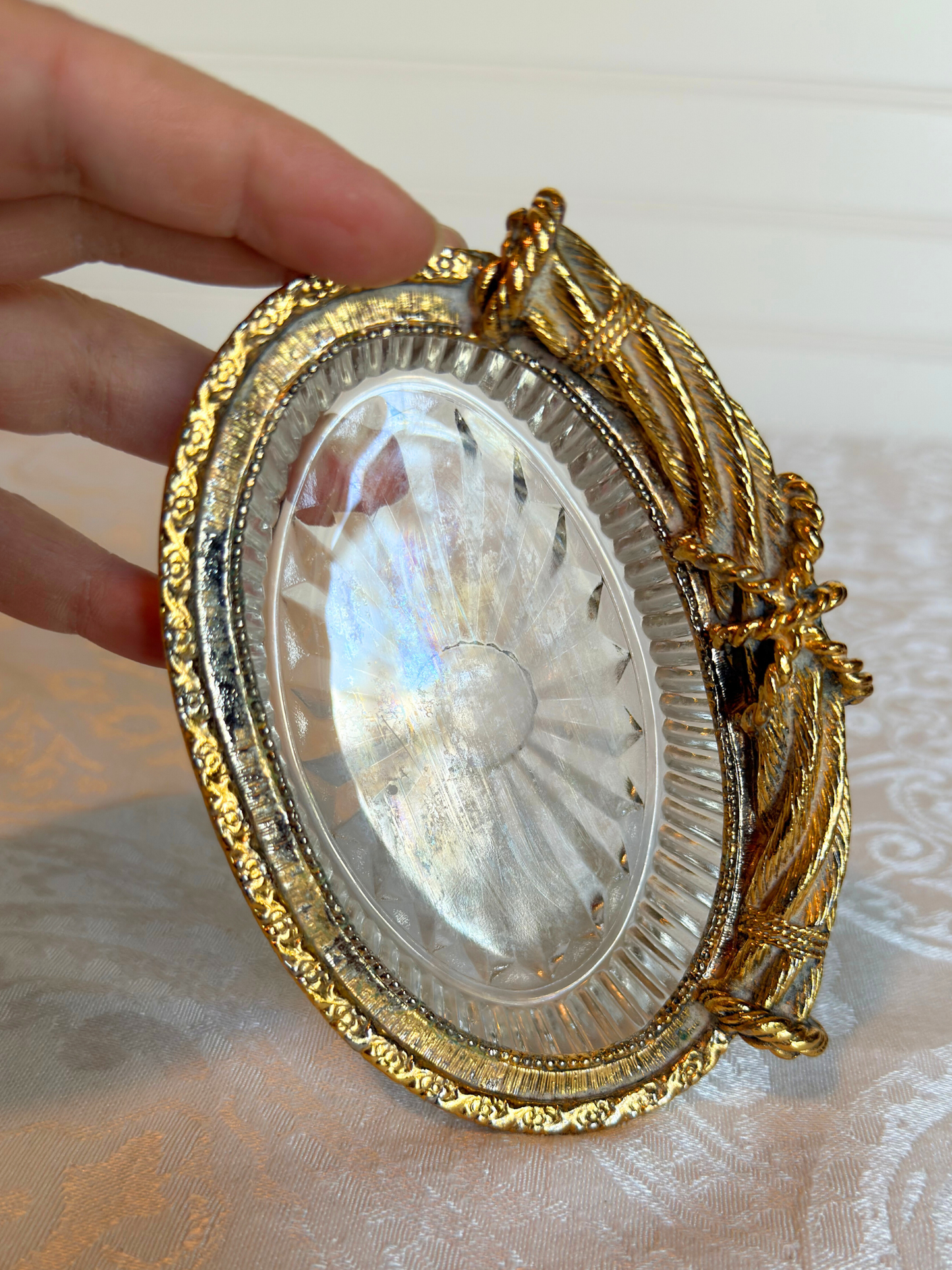 Decorative gold and glass dish held by a hand on a textured surface