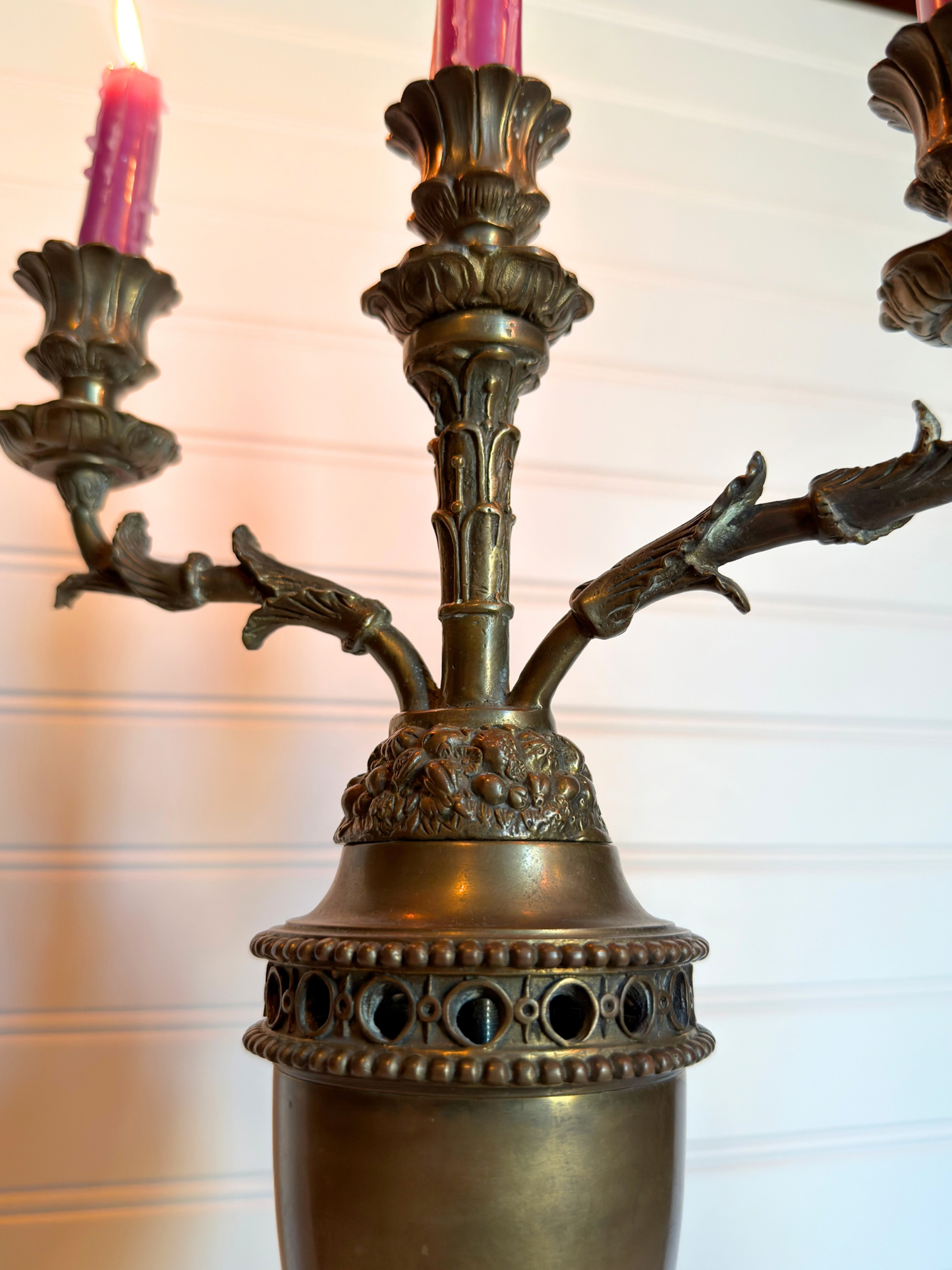 Bronze candle holder with pink candles against a white background