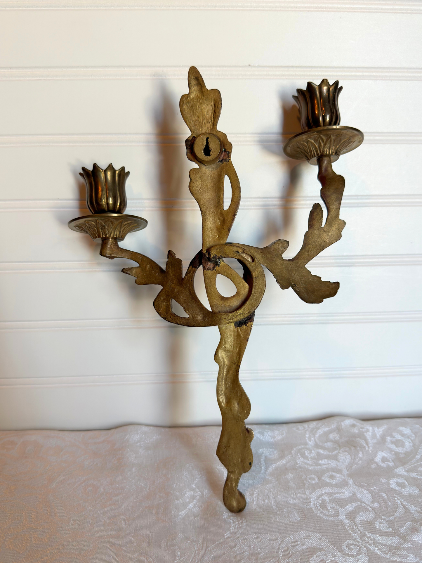 the back of ornate brass wall sconce on a white background