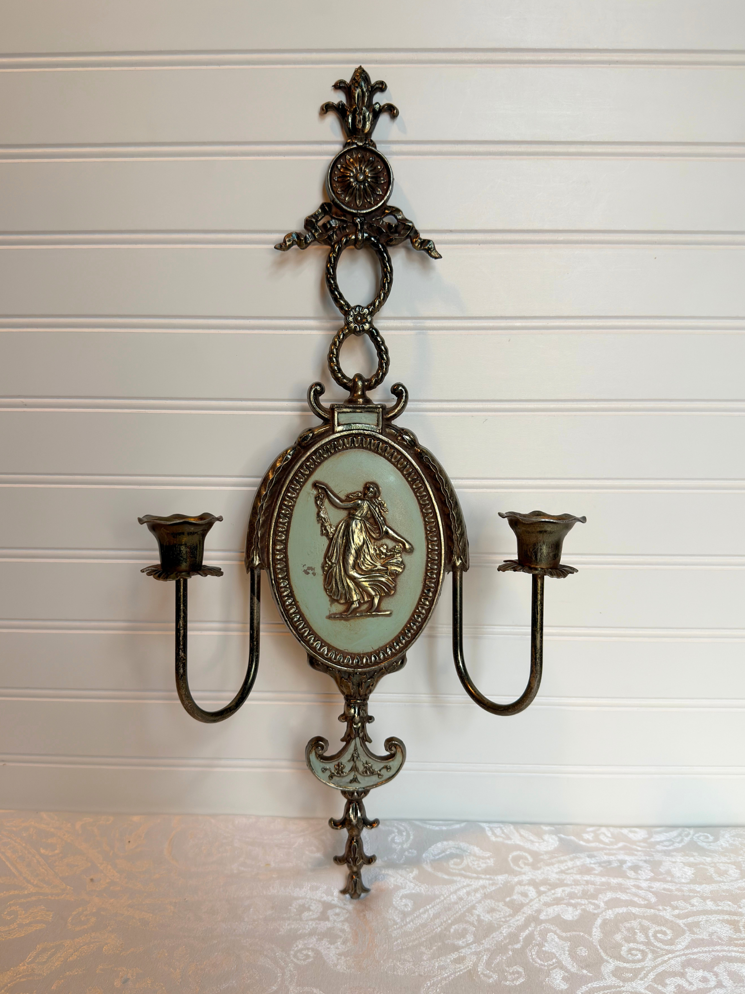 Decorative metal wall sconce with figurative lady design on a white background