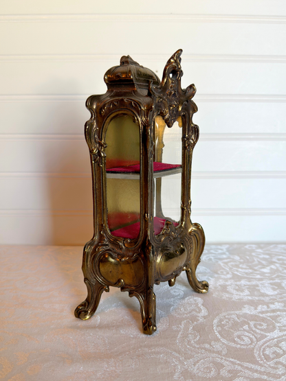 side of ornate vitrine jewelry box with red shelf on a white background