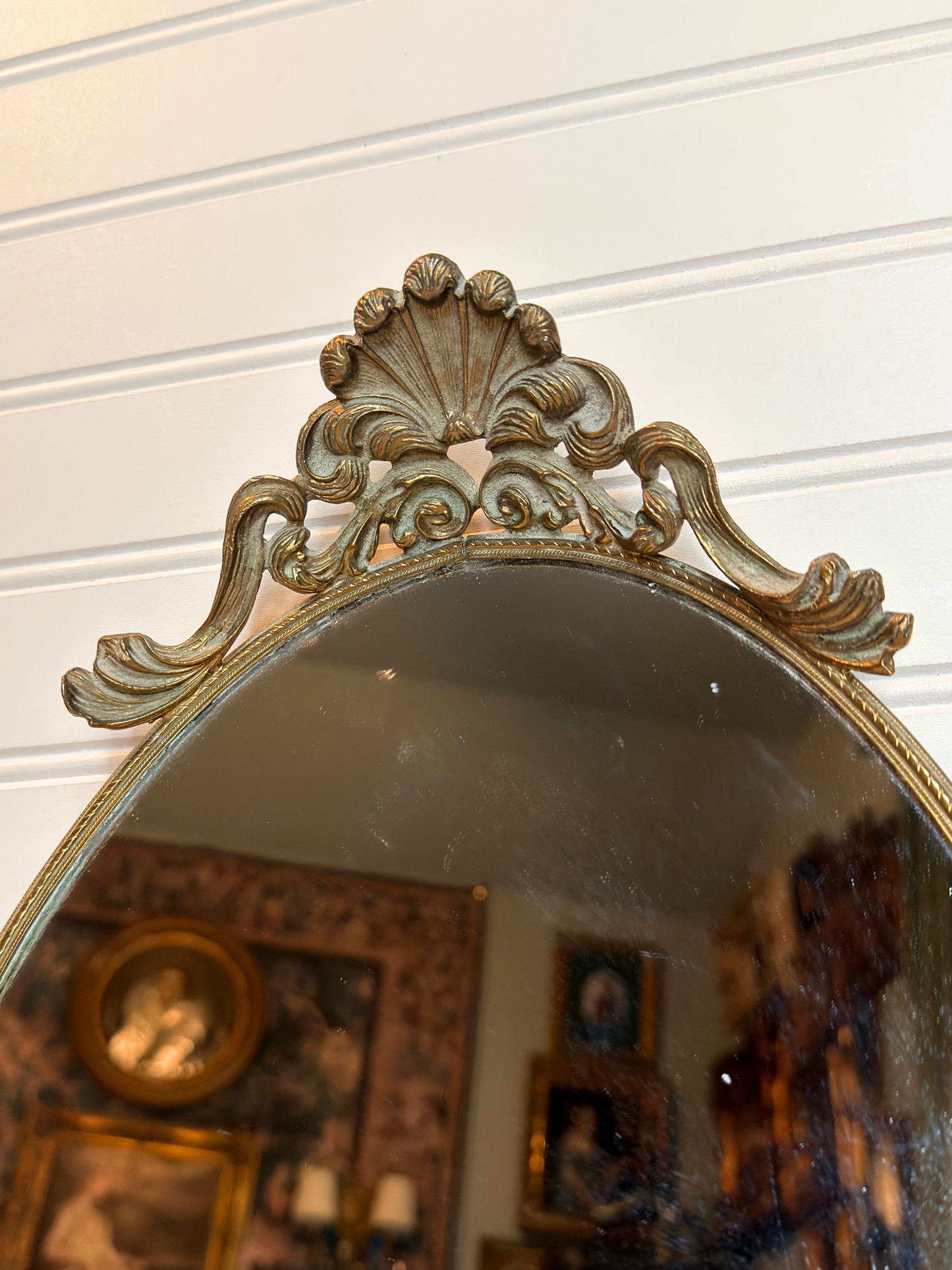 Decorative mirror with intricate gold frame on a white wall