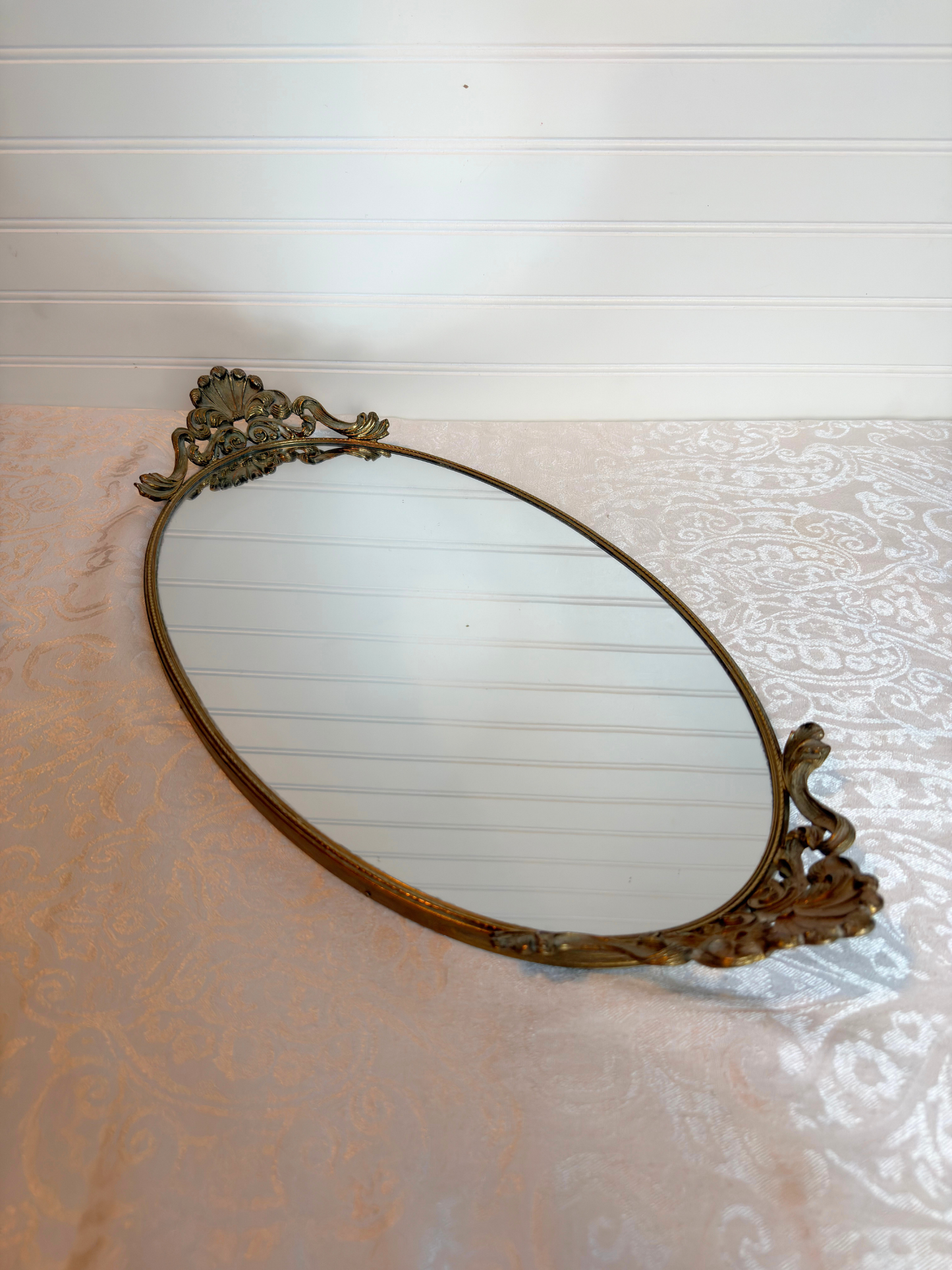 Decorative oval mirror with ornate frame on a textured surface
