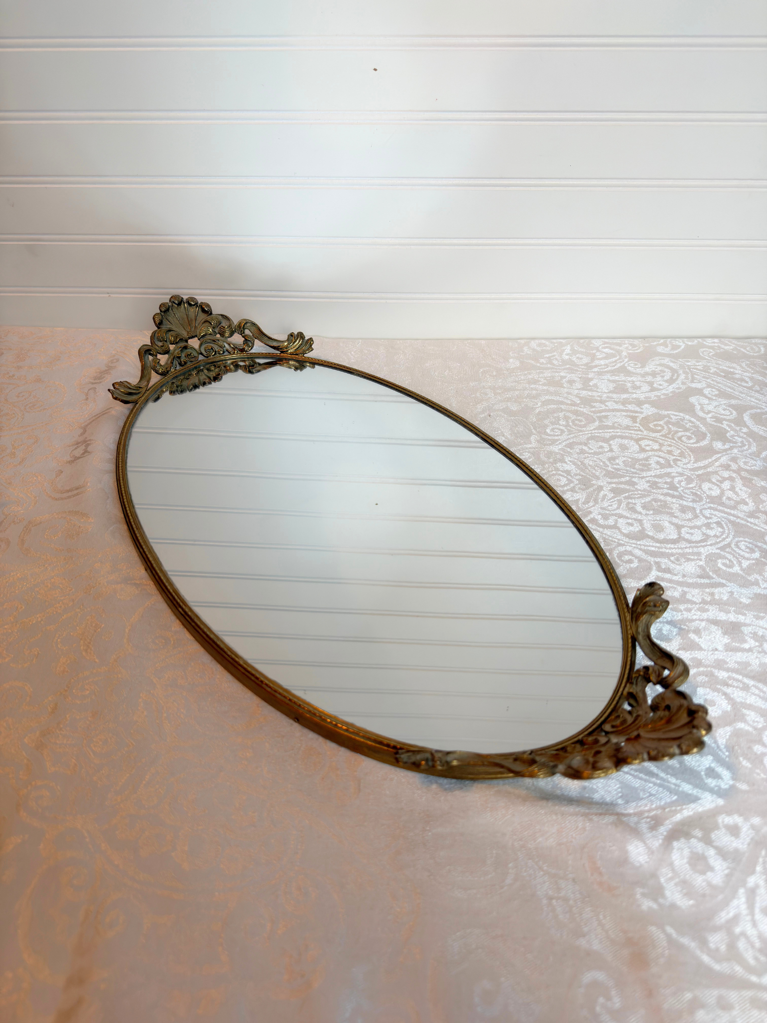 Decorative oval mirror with ornate frame on a textured surface
