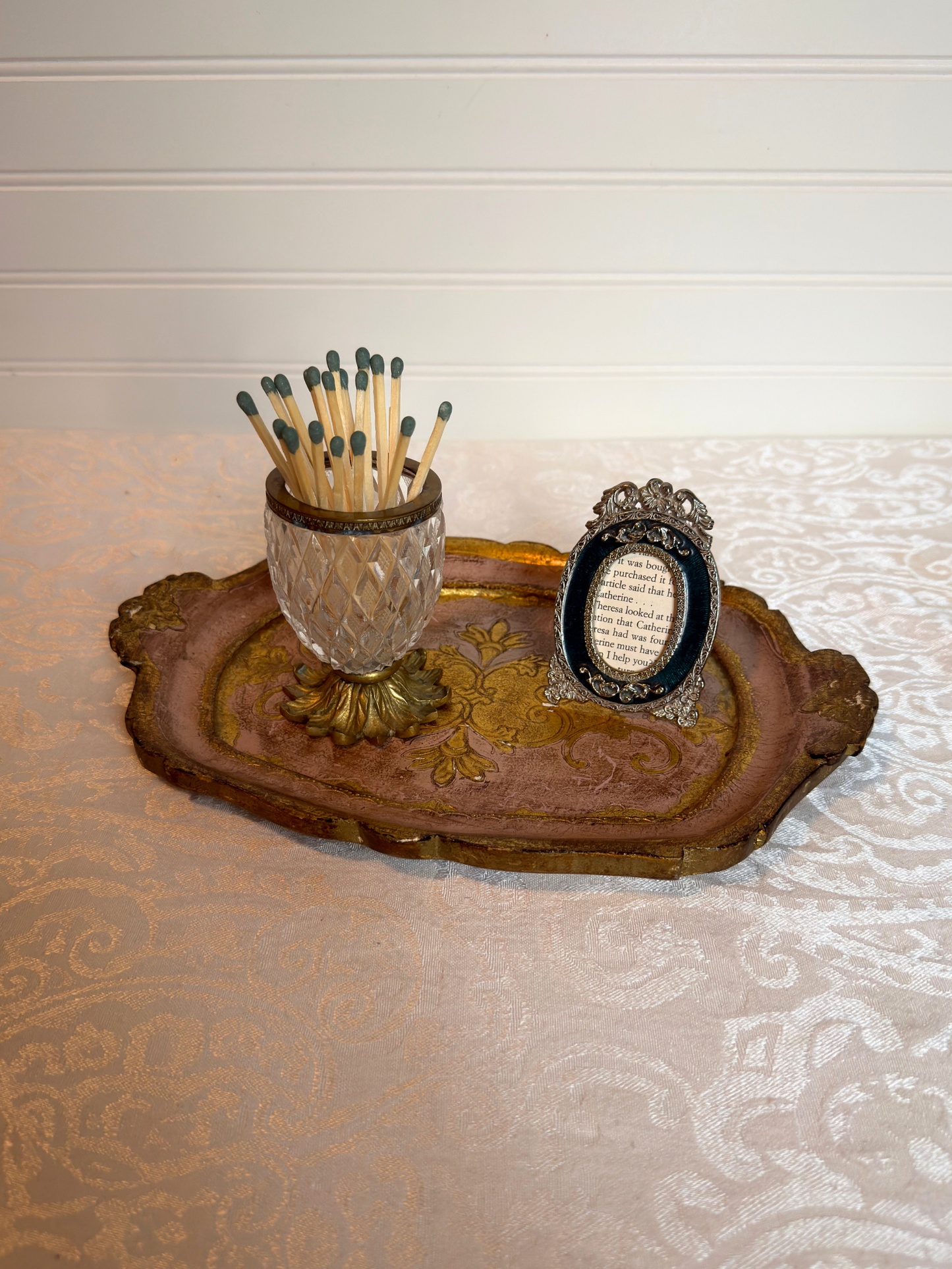decorative pink and gold wood tray with a crystal holder and tiny frame on a white background