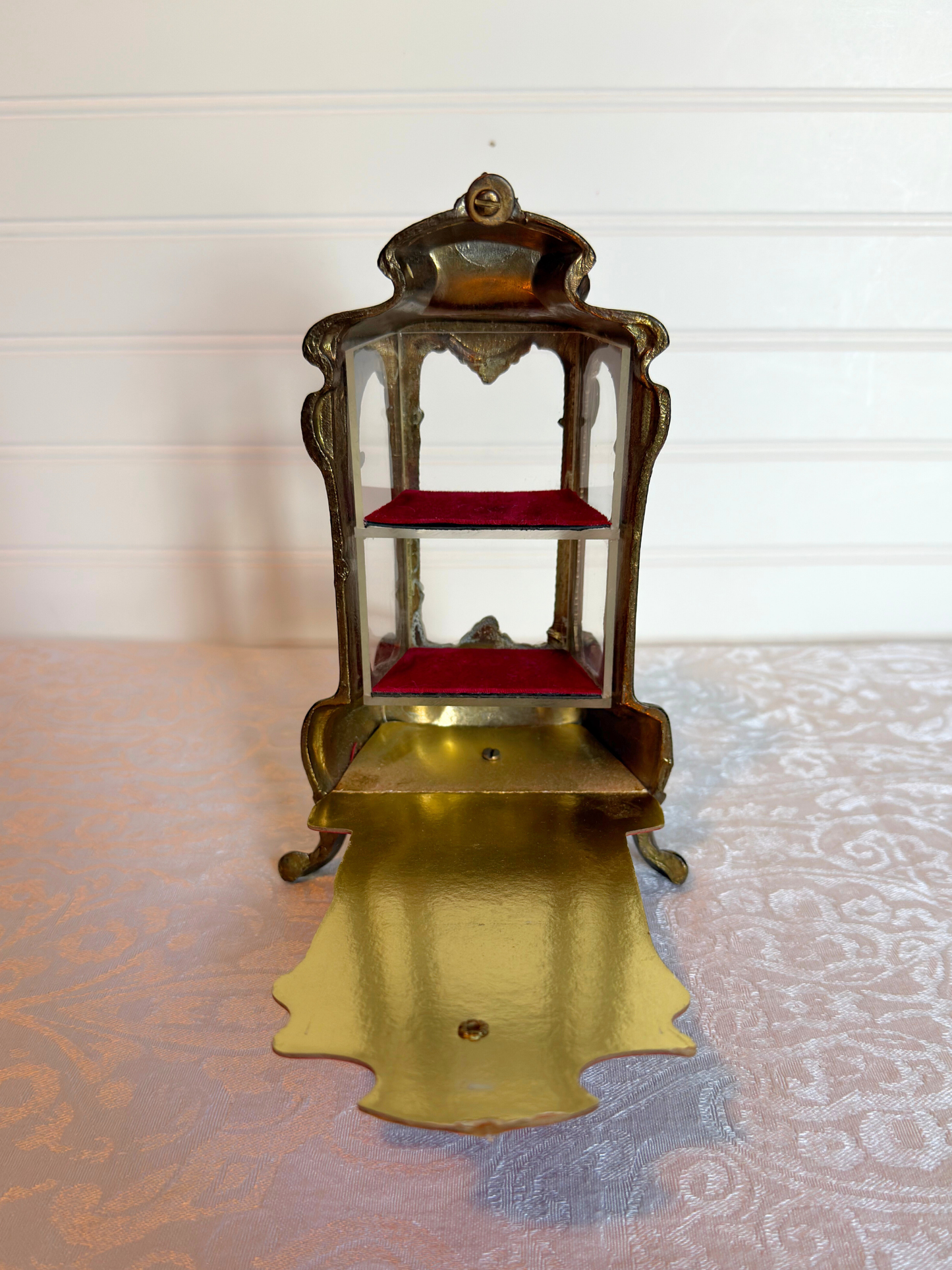 back of ornate vitrine jewelry box open with red shelf on a white background