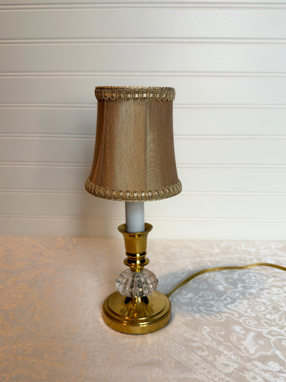 Small table lamp with a champagne base and decorative shade on a textured surface.