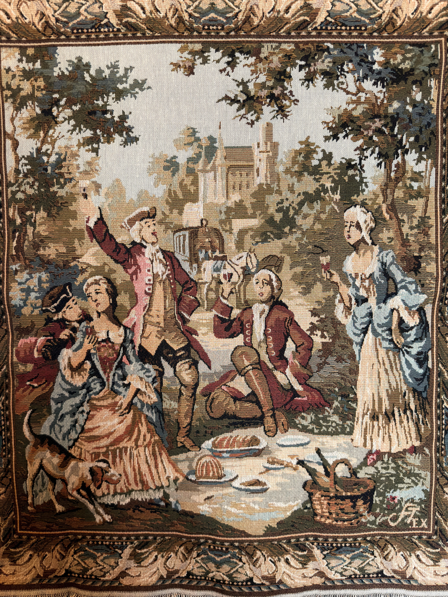 Tapestry depicting a classical scene with people at a picnic in a garden.