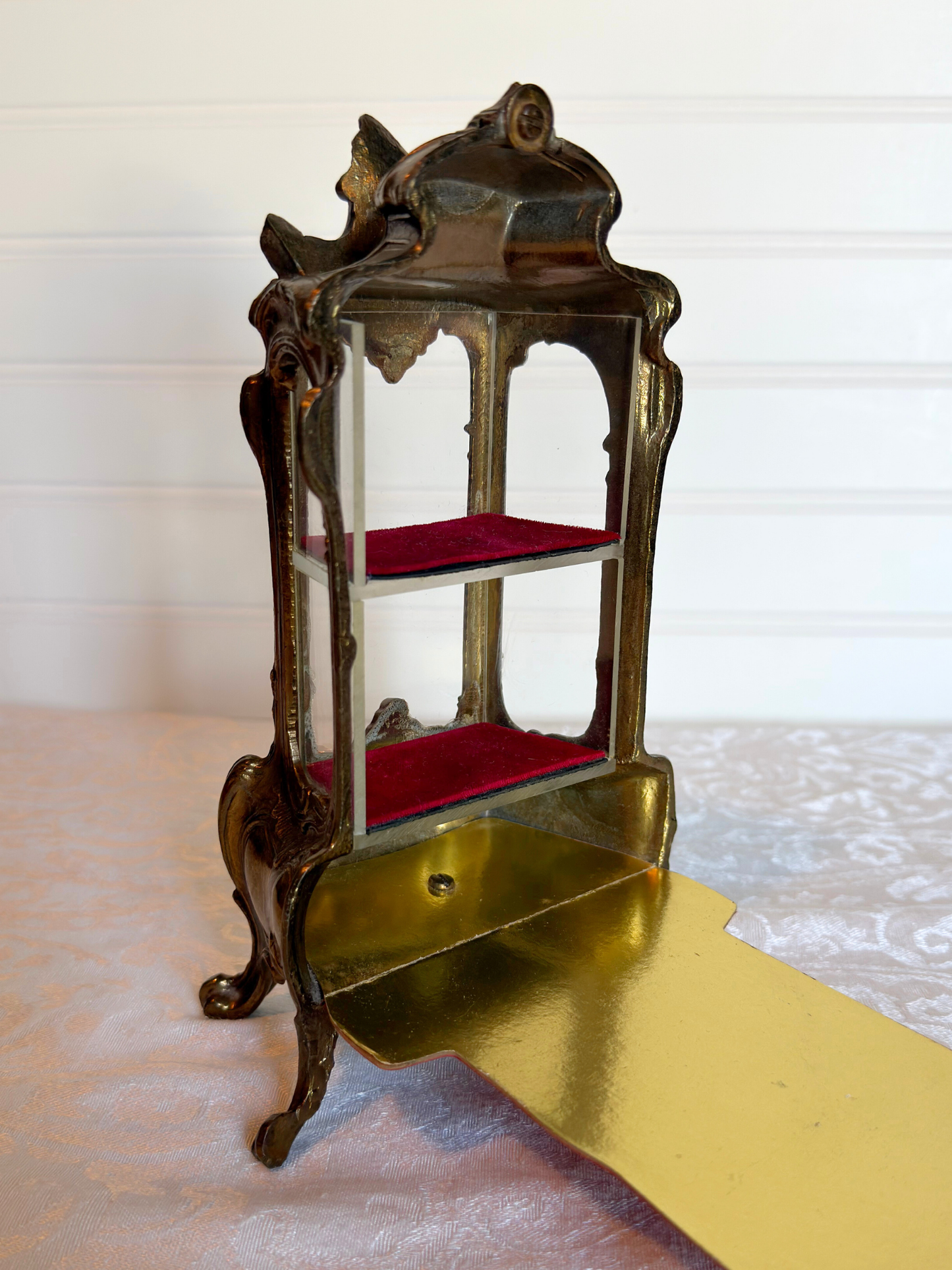 back of ornate vitrine jewelry box opened with red shelf on a white background