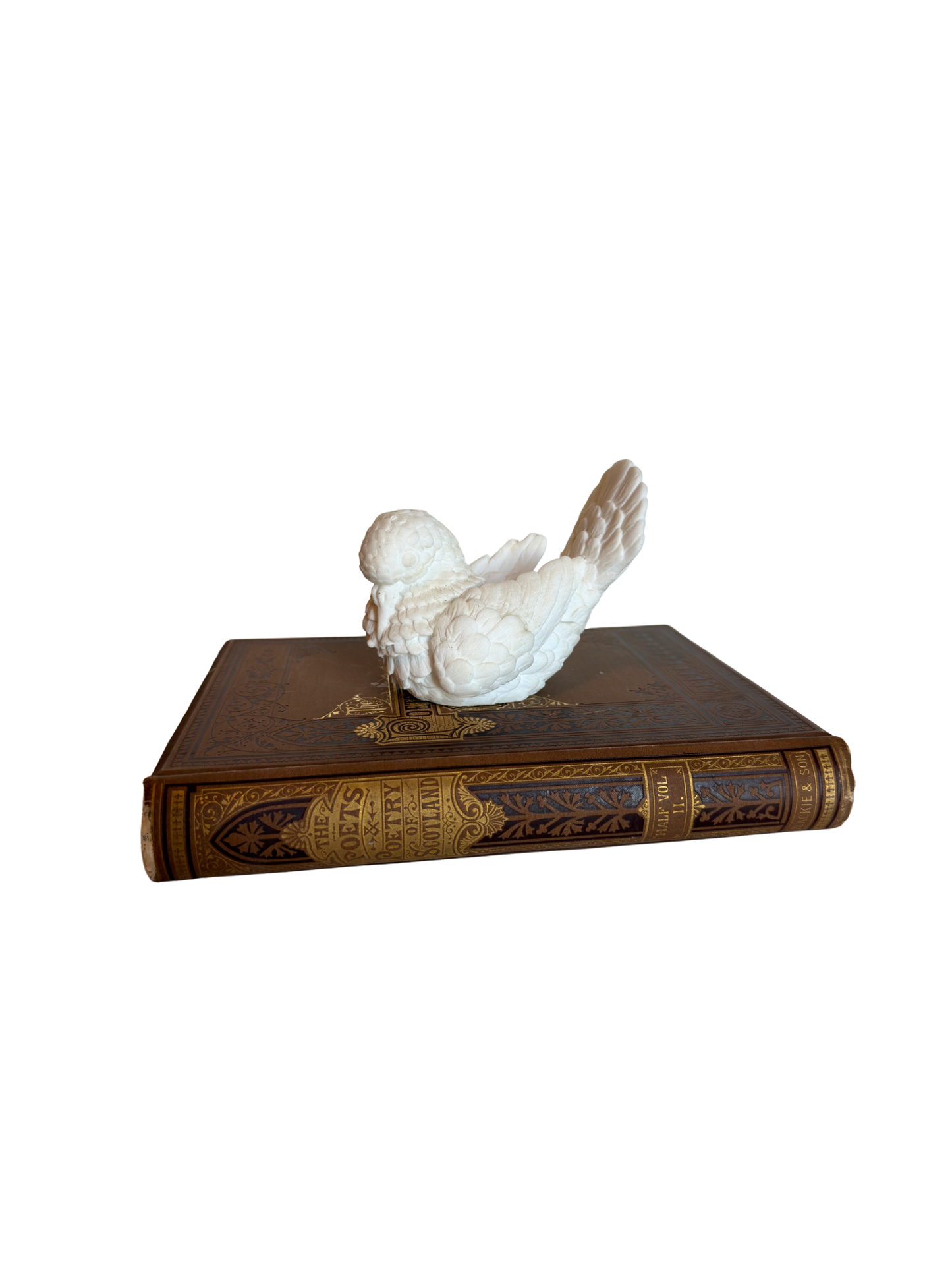 Decorative bird sculpture on an ornate book with a white background