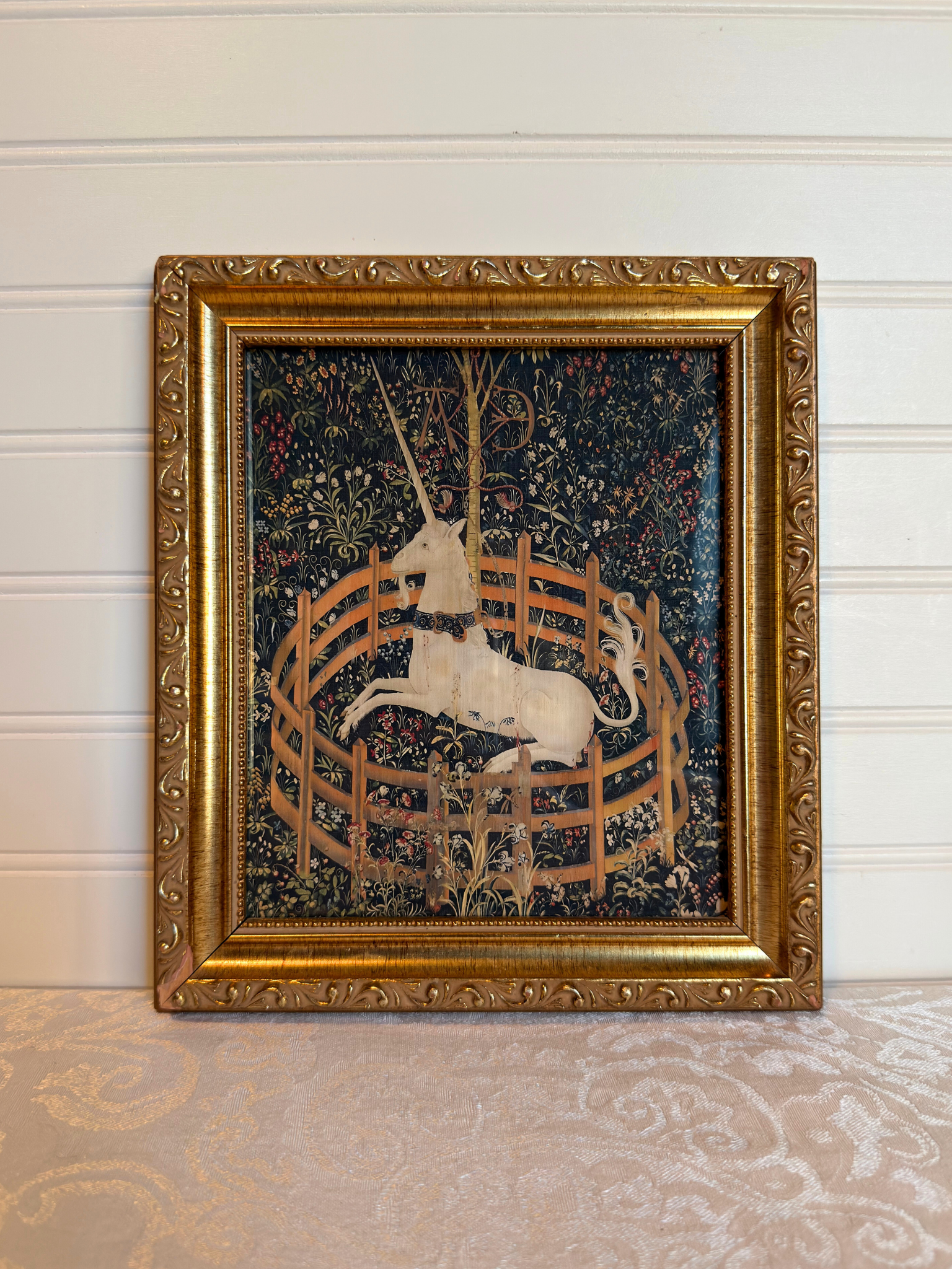 Decorative tapestry print with a unicorn in a gold frame on a white background