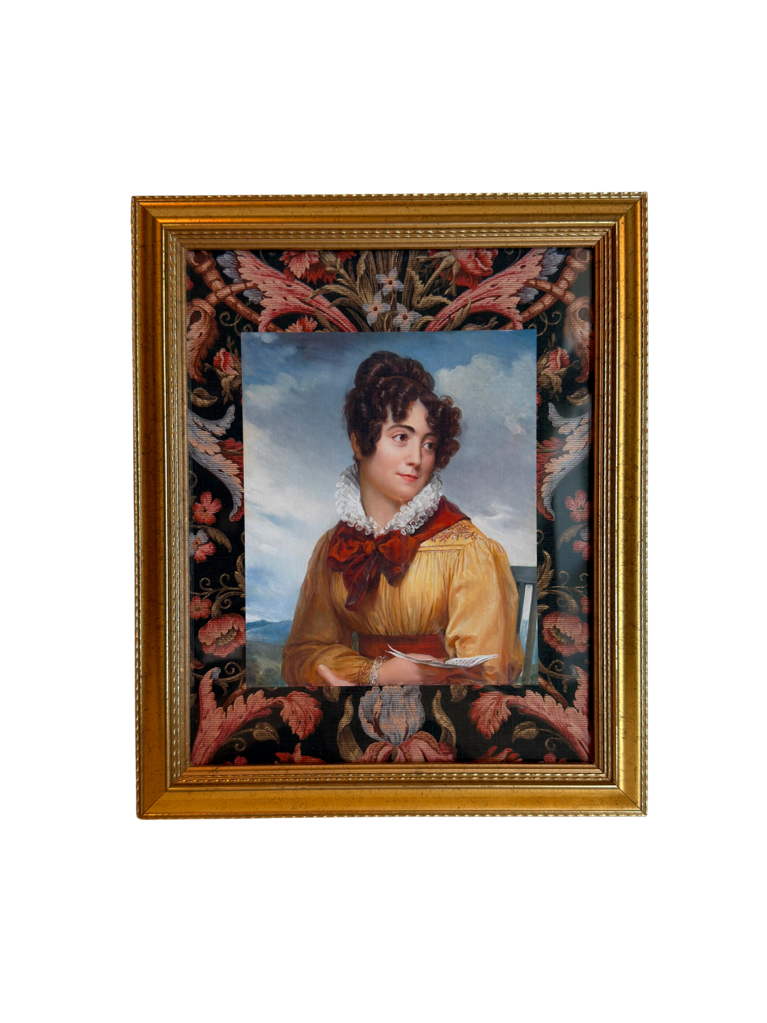 Gold framed portrait of a woman wearing a yellow and red dress holding a book with a decorative floral border