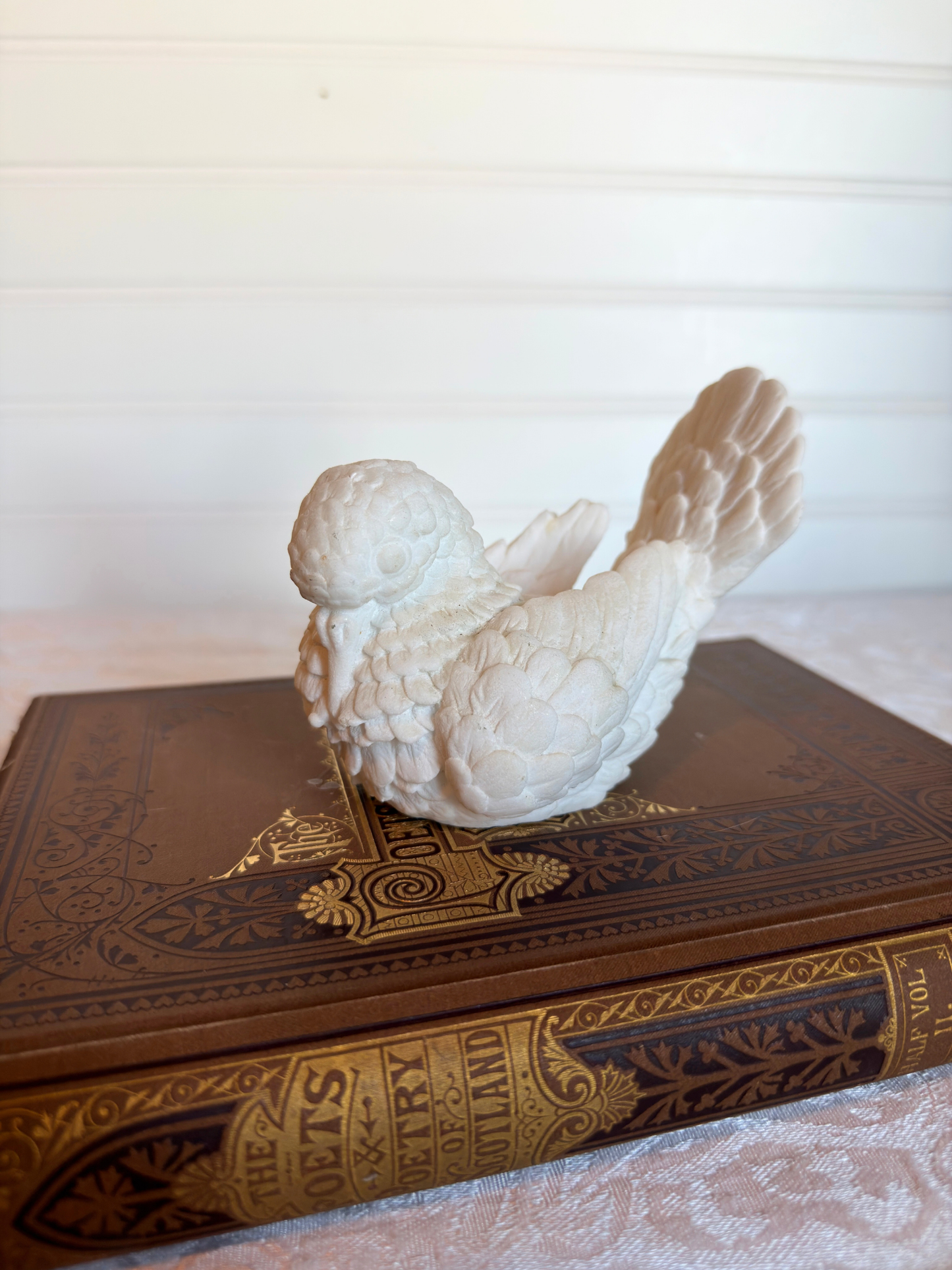 White dove sculpture on top of a vintage book with a blurred background