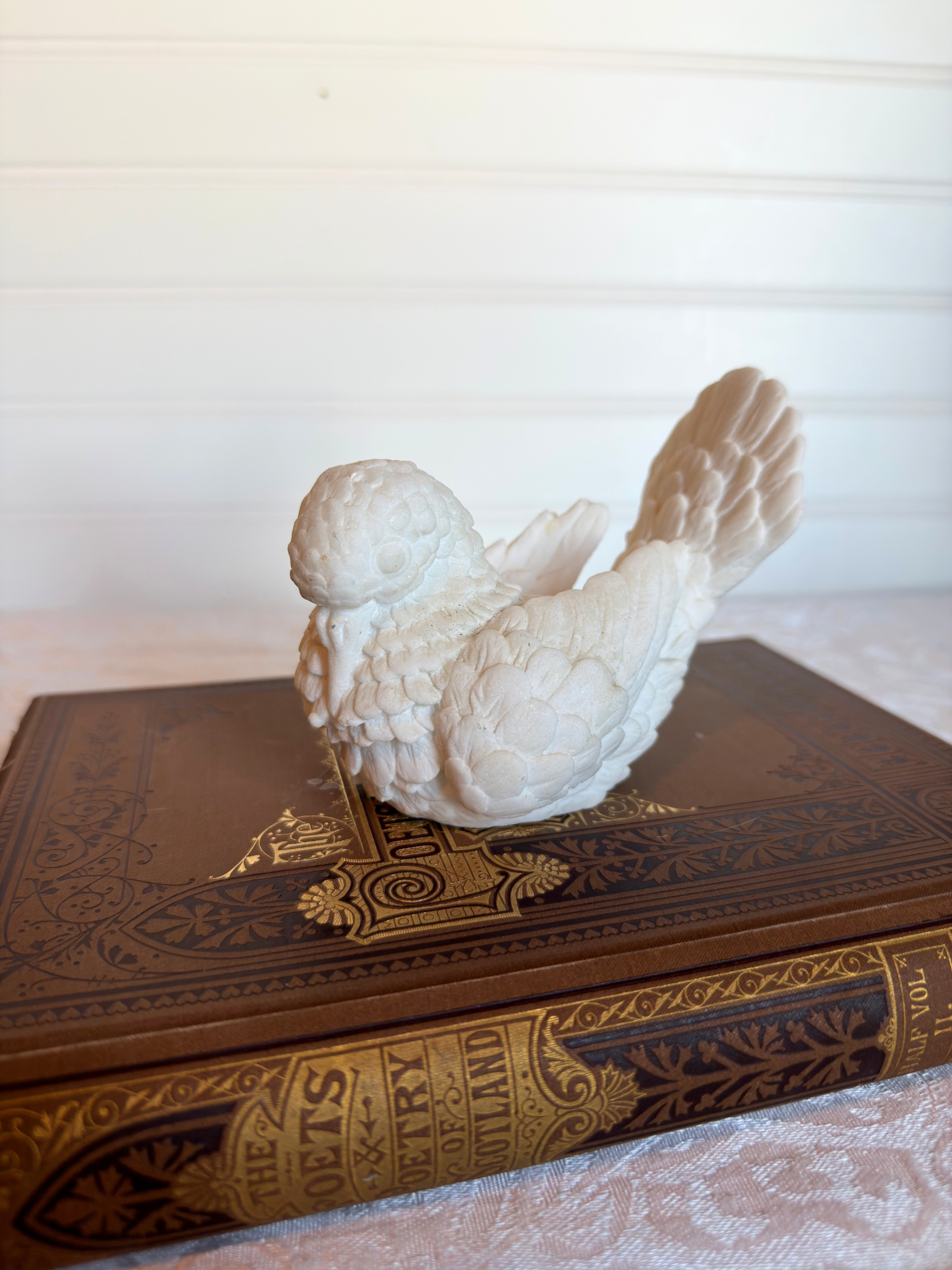 White dove sculpture on top of a vintage book with a blurred background