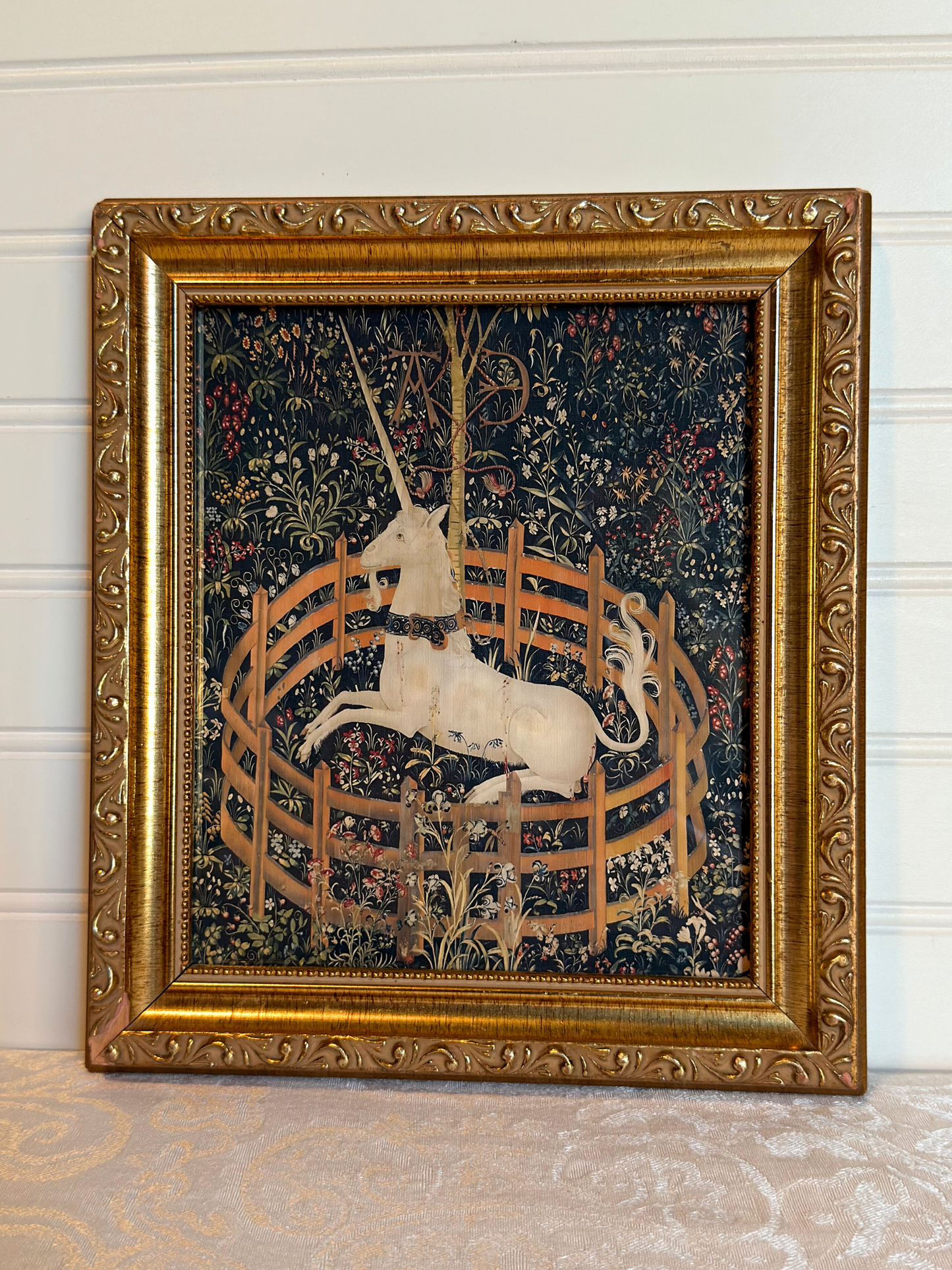 Decorative tapestry print with a unicorn in a gold frame on a white background
