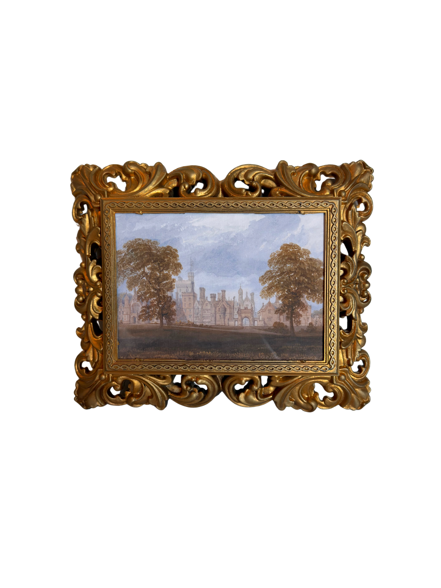 Decorative gold frame with a print of a landscape with trees and a manor house against a white background