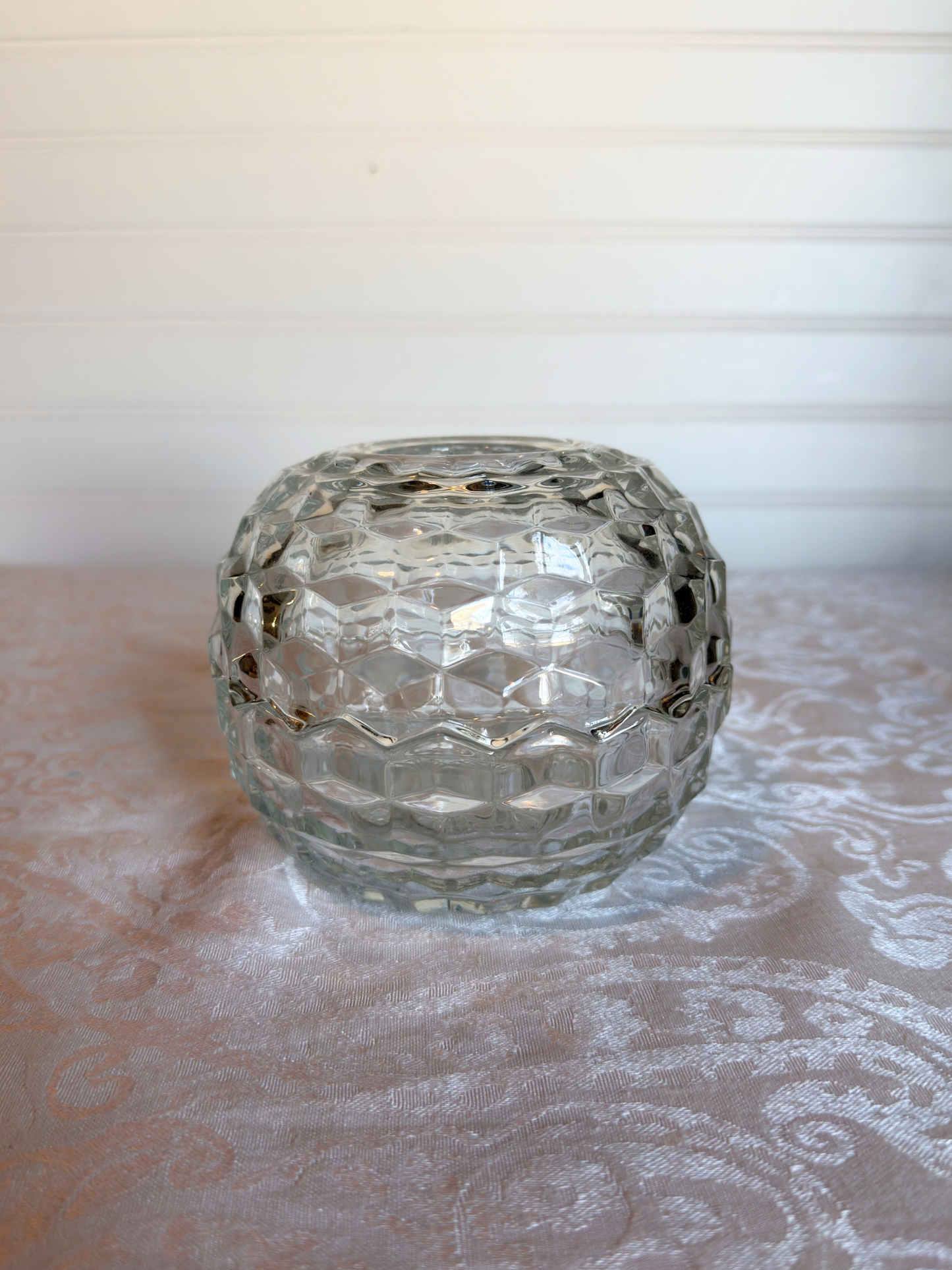 Clear glass candle holder on a textured surface with a blurred background
