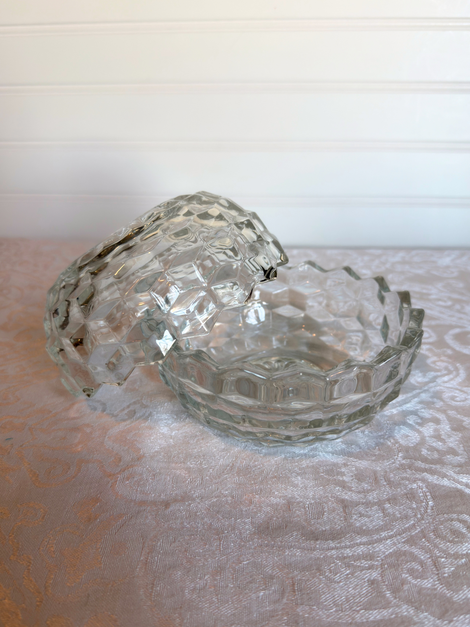 Clear glass candle holder opened on a textured surface with a blurred background