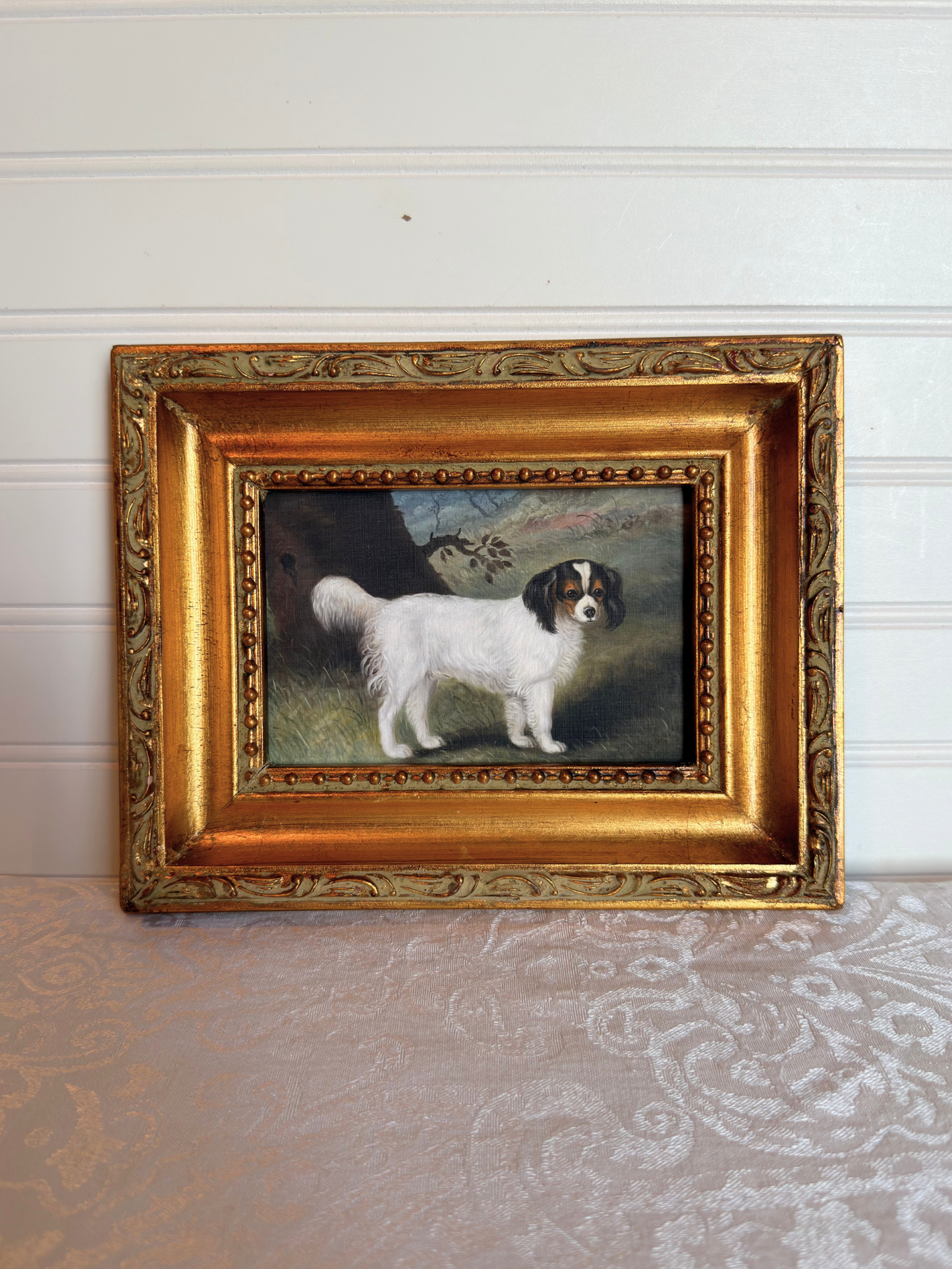 Small print of a white and black King Charles spaniel in a decorative gold frame on a white background