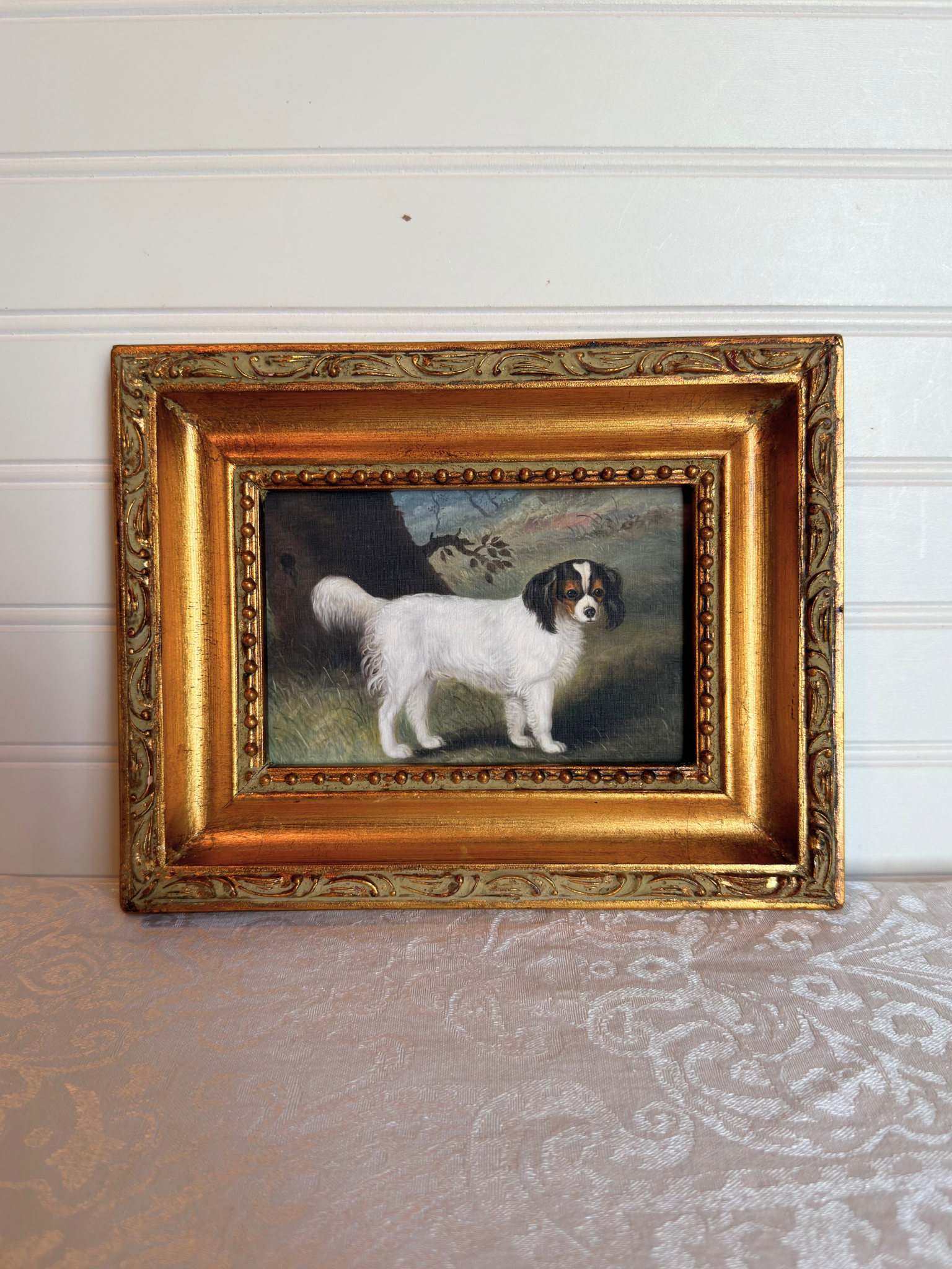 Small print of a white and black King Charles spaniel in a decorative gold frame on a white background