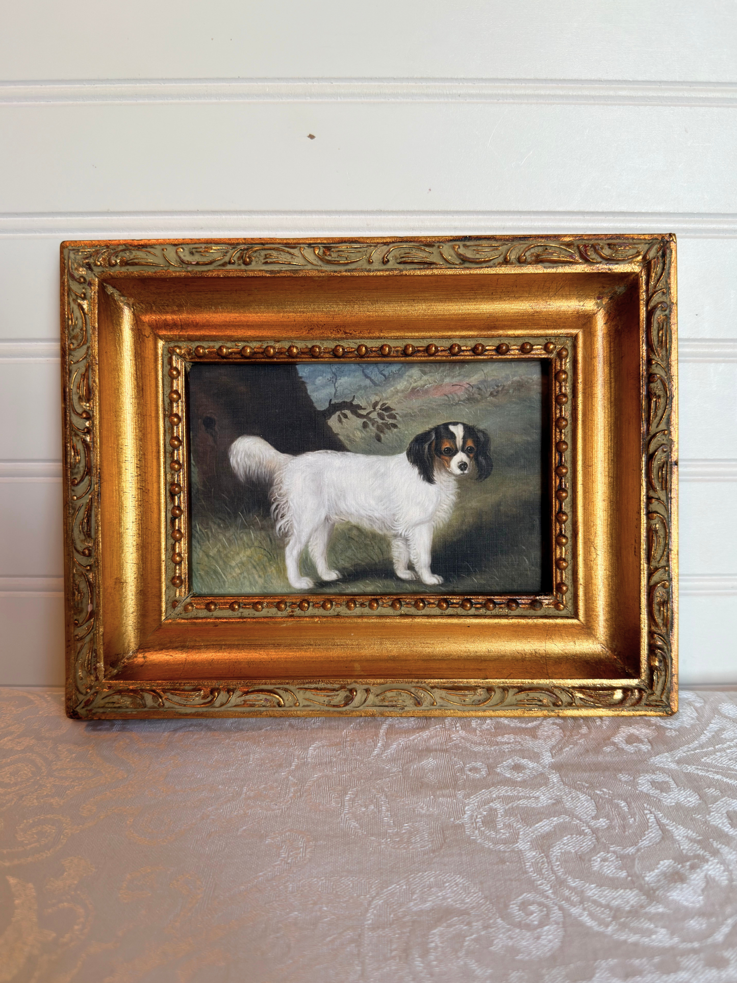 Small print of a white and black King Charles spaniel in a decorative gold frame on a white background