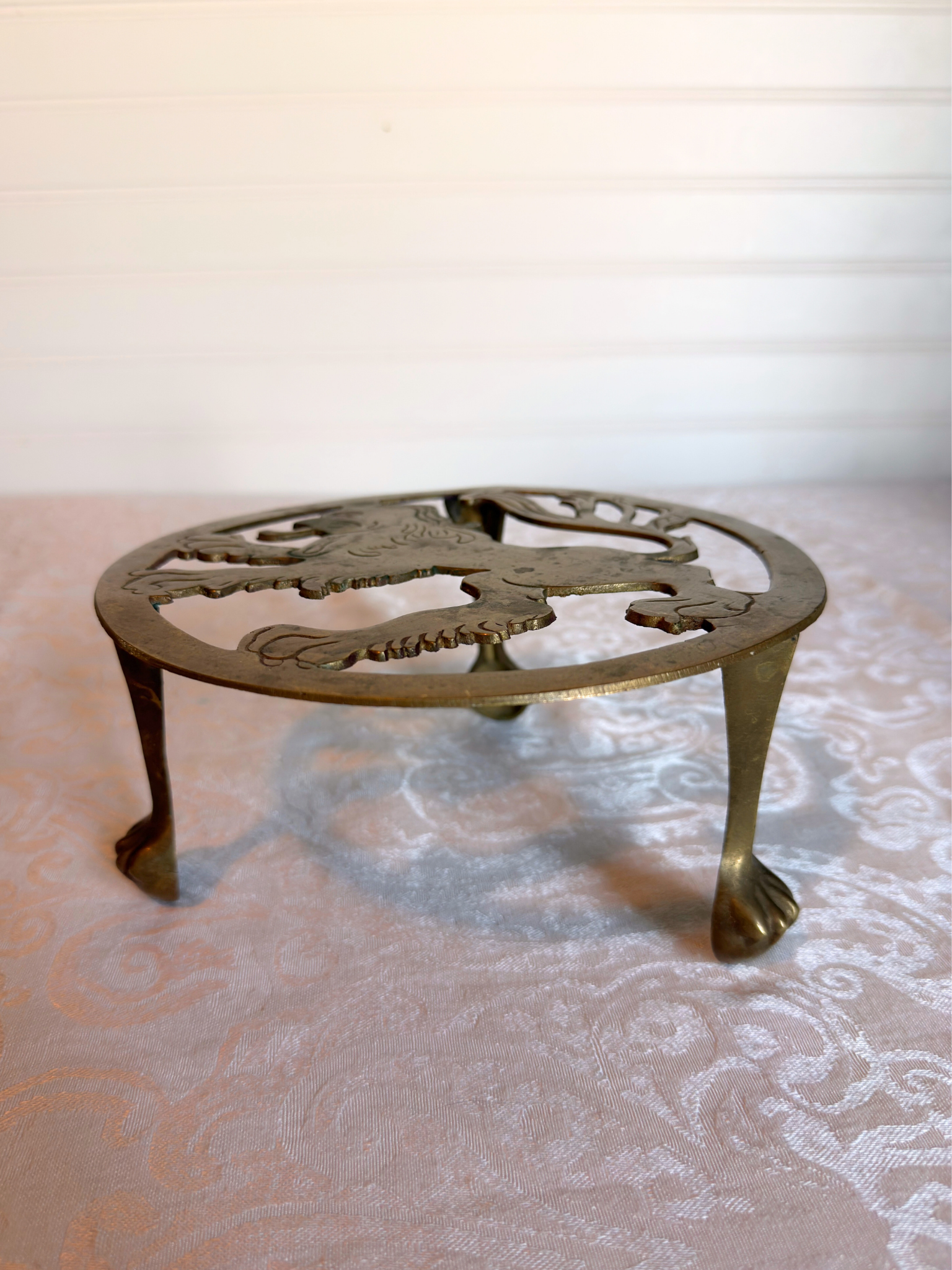 Decorative brass trivet with intricate design on a patterned surface