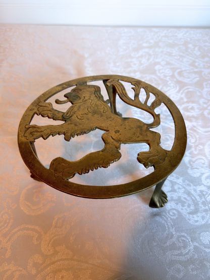 brass  trivet stand  with lion design on a textured surface