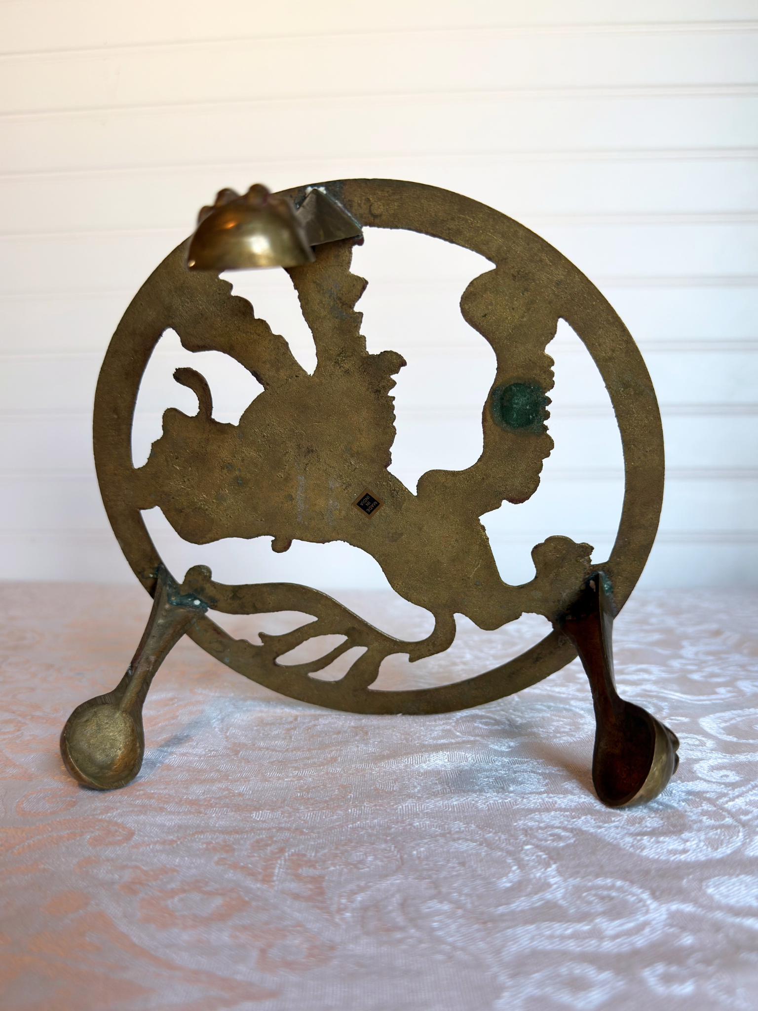 bottom of brass stand on white textured surface 
