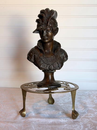 cast iron bust on a brass stand with a white background