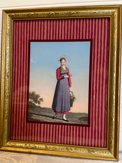 Framed artwork of a woman in a dress holding a basket on a red striped background