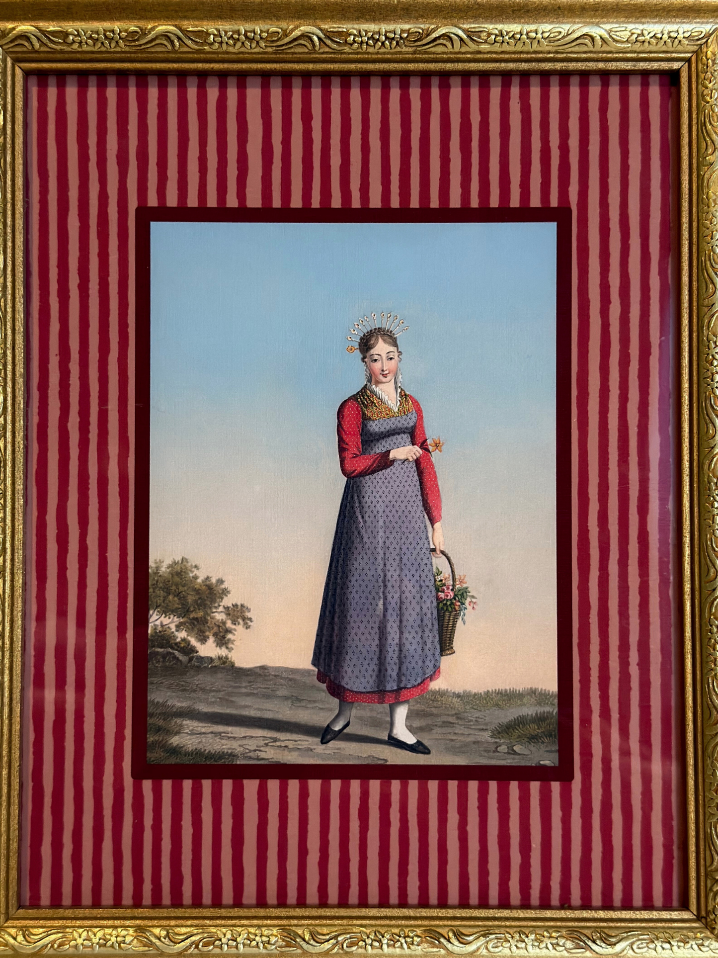 Framed artwork of a woman in a dress holding a basket on a red striped background
