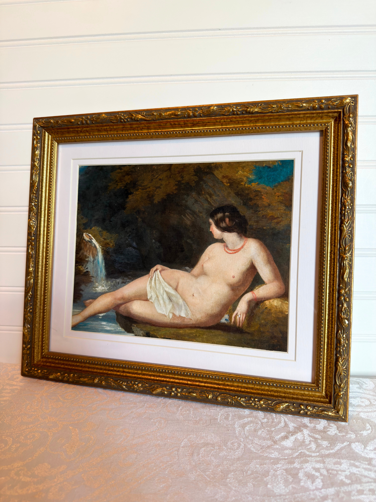 Framed print of a nude woman by a waterfall with a gold frame.