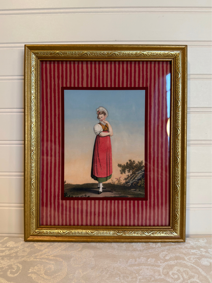 Framed artwork of a woman in a red dress, with a gold frame and red striped inner lining.