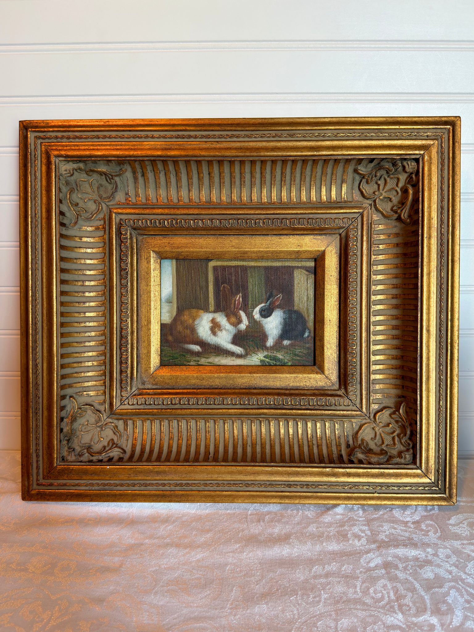 Framed painting of two rabbits on a textured surface with a white background