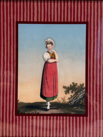 Framed artwork of a woman in a red dress, with a gold frame and red striped inner lining.