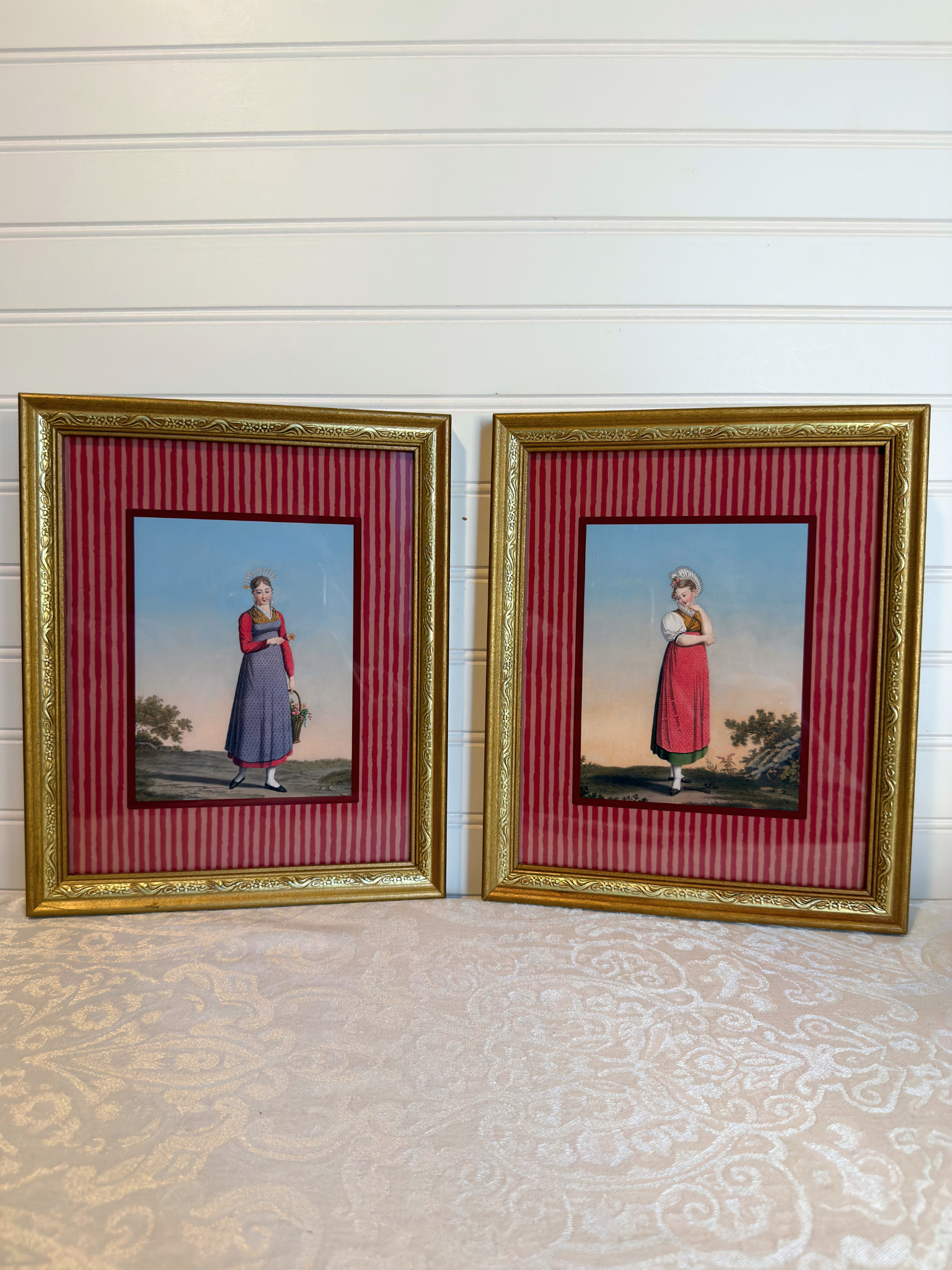 Framed artwork of a woman in a red dress, with a gold frame and red striped inner lining.
