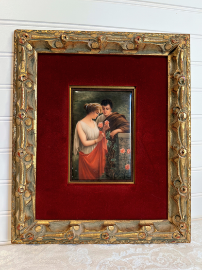 Small painting of couple with roses  within a decorative gold frame on a red background