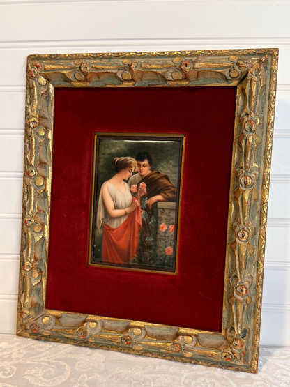 Small painting of couple with roses  within a decorative gold frame on a red background