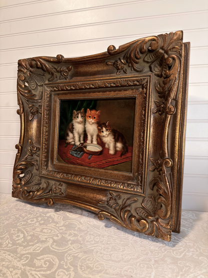 Decorative painting of three cats in a ornate frame on a textured surface.
