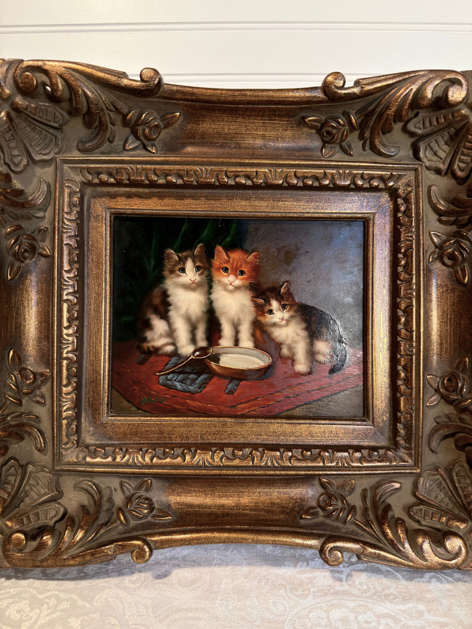 Decorative painting of three cats in a ornate bronze frame.