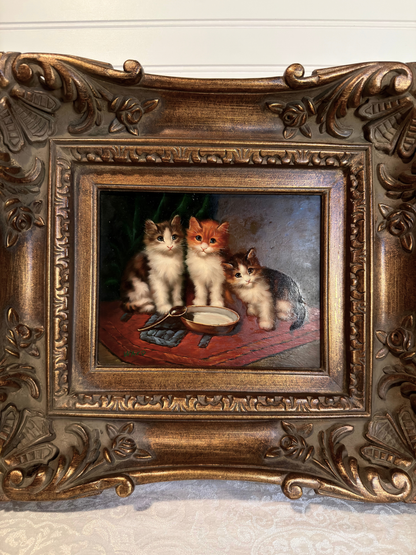 Decorative painting of three cats in a ornate bronze frame.