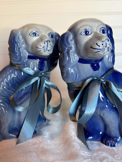 Two blue Staffordshire dogs with blue ribbons on a textured white background