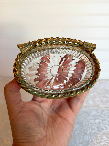 Decorative glass dish with gold rim held in a hand against a neutral background