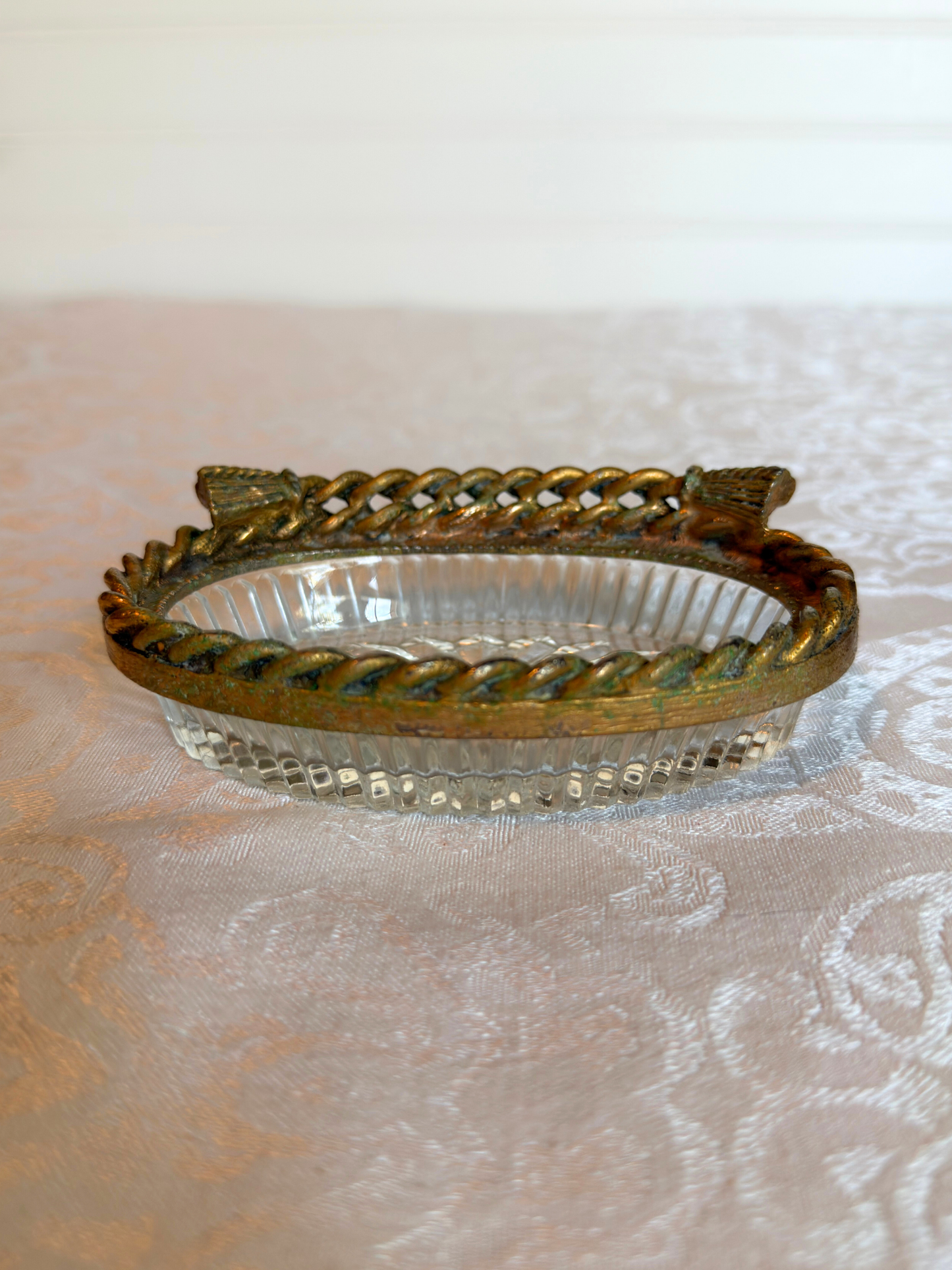 Decorative glass dish with gold rim on a textured white background
