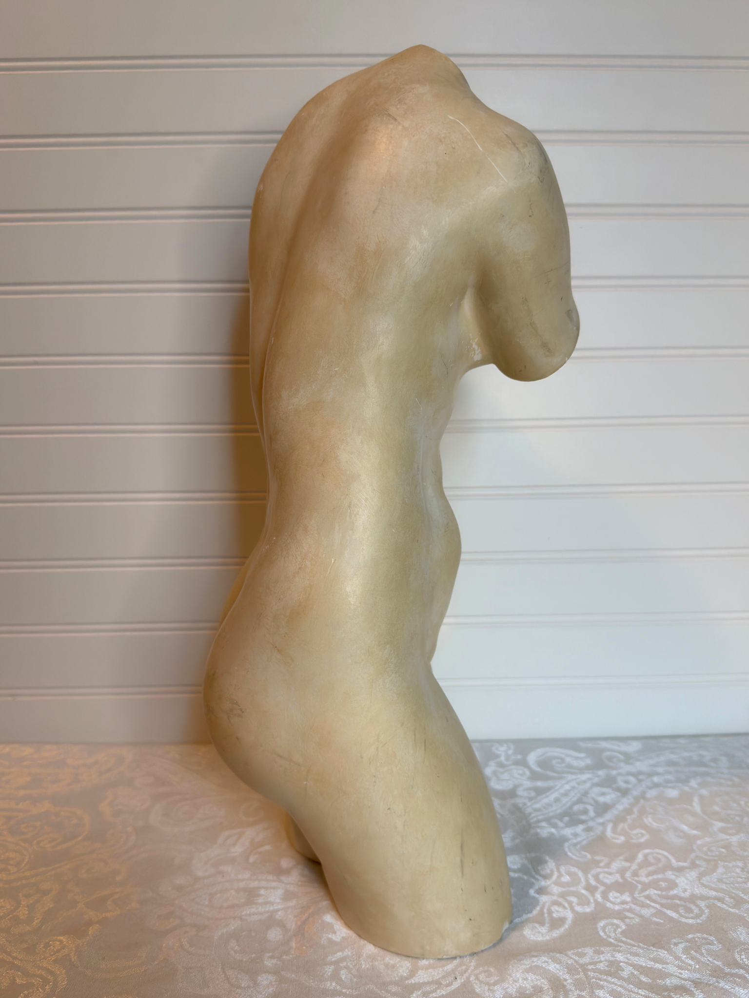  sculpture of a nude figure on a textured surface with a neutral background