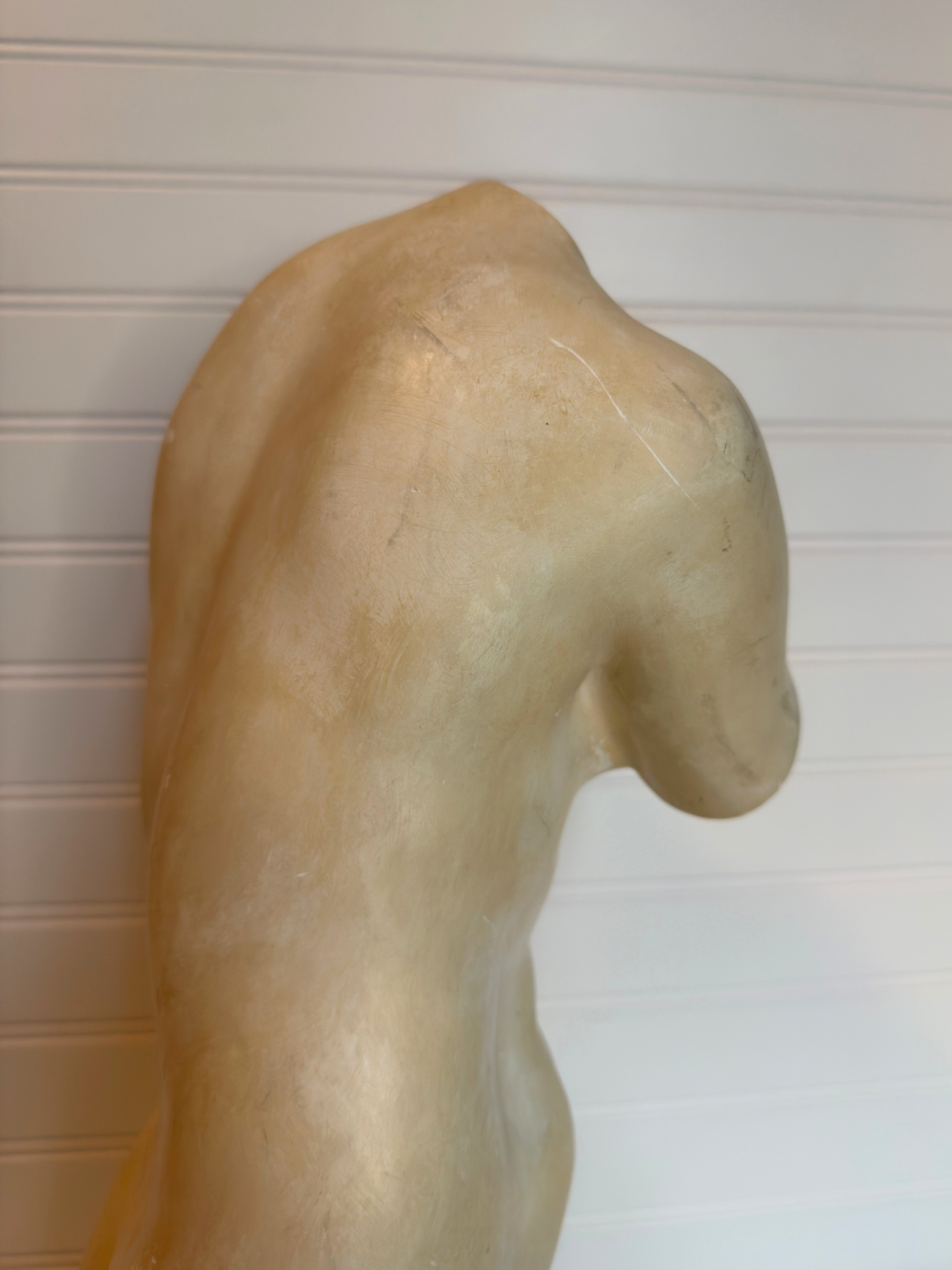 Statue of nude torso against a plain background