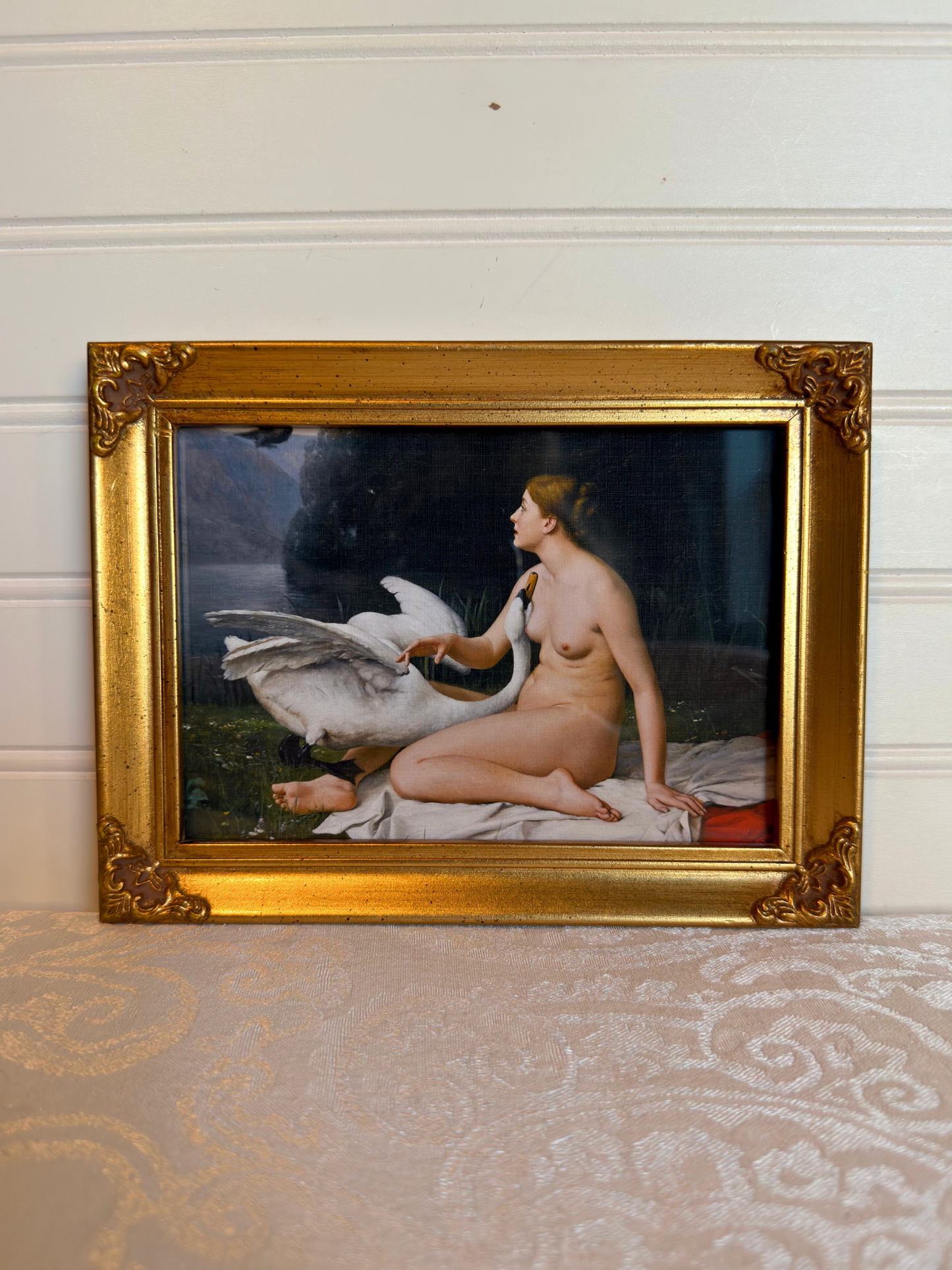 print of nude lady and a swan  in a gold frame on a white background