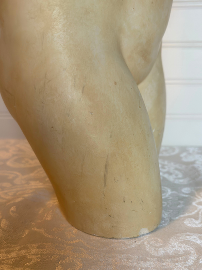 Close-up of  sculpture of a nude figure on a wooden base.